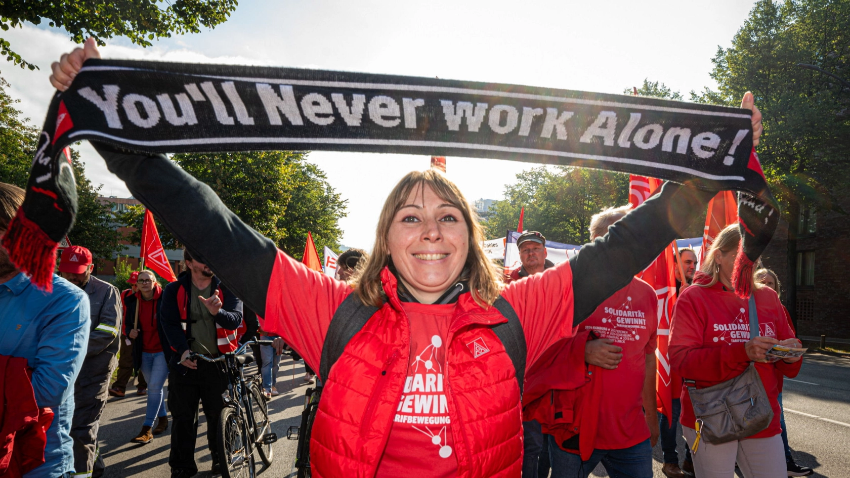 Eine Frau hält einen Schal hoch mit der Aufschrift „You never work alone“
