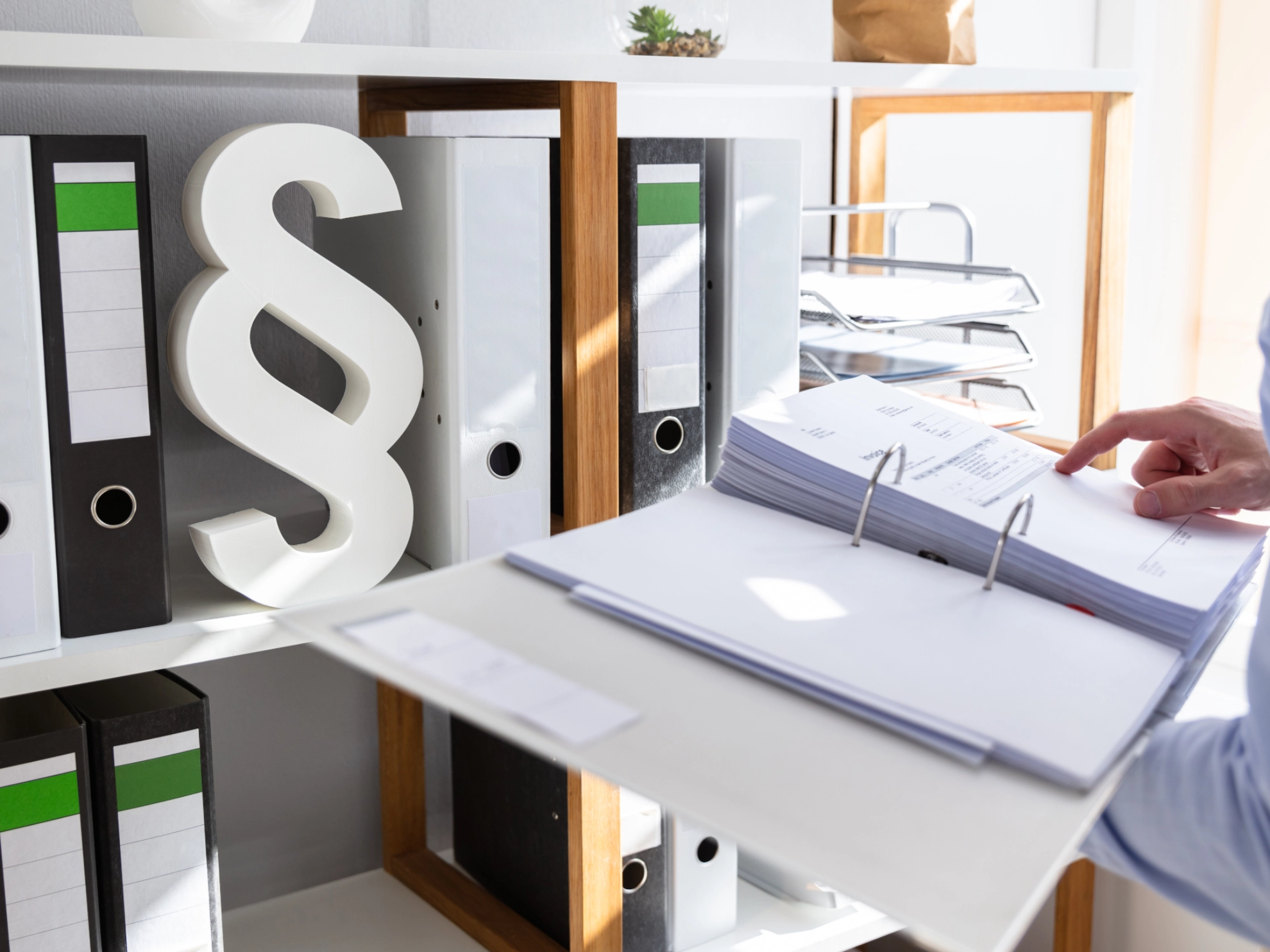 Mann steht im Büro und öffnet Ordner, Klausel im Regal im Hintergrund