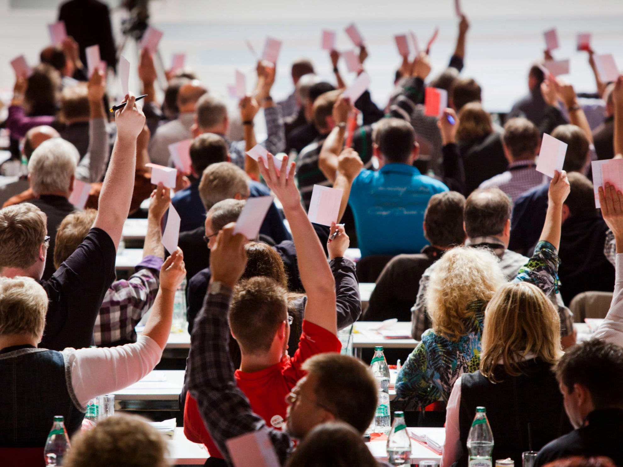 Menschen heben die Hände bei einer Abstimmung.